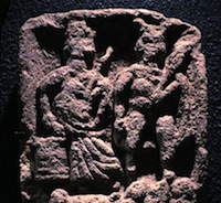 carving of pair of seated gods, female to the left and horned male to the right